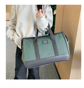 Close-up of large canvas travel bag in dark green with black leather handles and logo