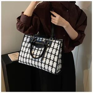Detail of black and white tweed tote bag showing woven texture and leather handle