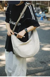 Outdoor shot of ivory nylon dumpling bag showing large capacity and soft drape effect