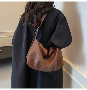 Gros plan sur le sac hobo marron montrant la texture du cuir grainé et les détails dorés