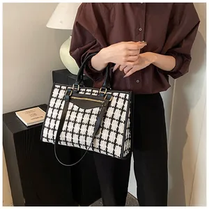 Detailed view of women's black and white tweed tote bag with leather straps on a model
