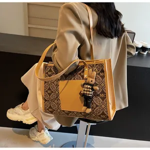 Brown tote bag with MC 1989 monogram pattern and cute rabbit charm on a model