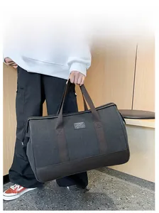 Detail of dark grey canvas travel bag featuring durable black leather base and wide handles