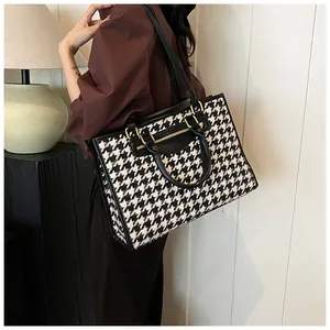 Black and white houndstooth tote bag shown on shoulder for size and fit perspective