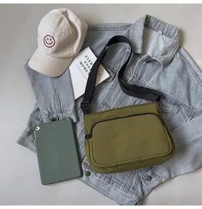 Détail de la sacoche en toile vert olive assortie à une veste en jean et accessoires