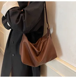 Détail de la texture cuir grainé marron foncé sur un sac hobo souple en forme de croissant