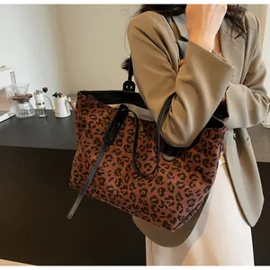 Brown leopard print large tote bag with black leather straps in a cafe setting