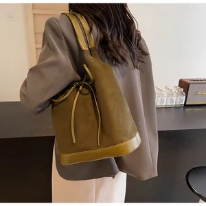 Close-up of olive green matte suede bucket bag shown in a stylish lifestyle setting