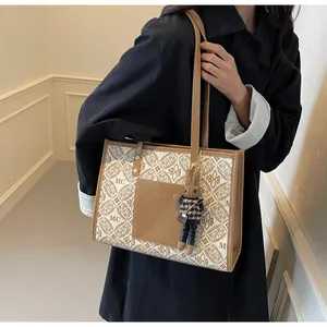Detail of printed tote bag featuring geometric monogram patterns and a rabbit charm