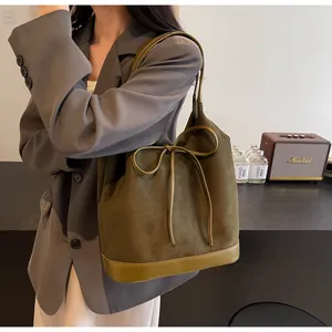 Detail of army green suede tote bag with drawstring bow and smooth leather base splicing