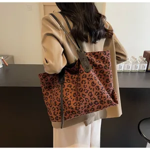 Back view of model wearing a large leopard print tote bag with black leather straps