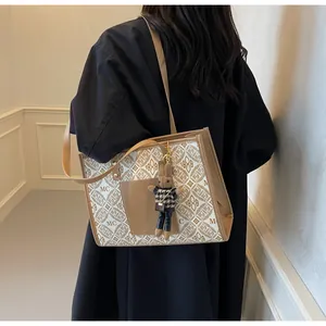 Detail of a beige monogram tote bag with brown trim and a cute rabbit charm accessory