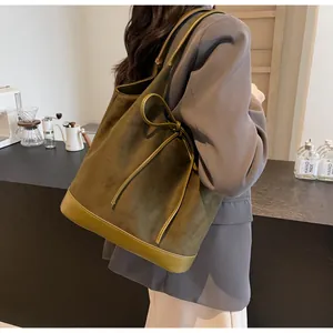 Close-up of olive green tote bag featuring bow detail and suede leather texture