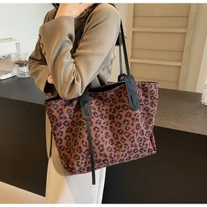 Detail view of large leopard print tote bag with black straps in a cafe setting
