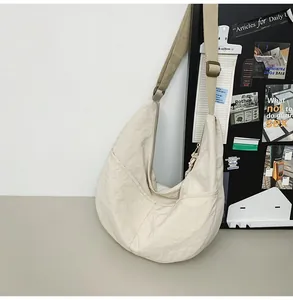 Detail of cream nylon dumpling bag featuring crinkled texture and adjustable strap