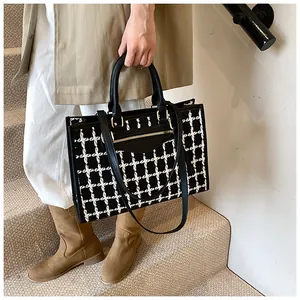 Detail of black and white tweed tote bag with leather straps on staircase