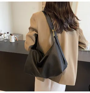 Gros plan détaillé sur la texture grainée et les boucles dorées de ce grand sac hobo noir