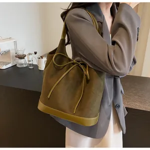 Detail of dark green suede tote bag featuring a decorative bow and leather splicing texture