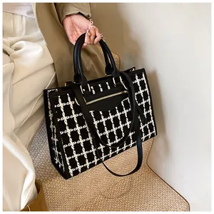 Detail of tweed tote bag showing black and white checkered texture with gold hardware