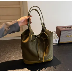 Detail of olive green tote bag featuring suede texture and decorative leather bow