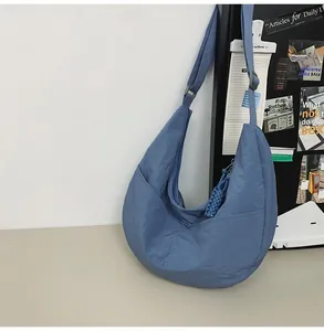 Detail of blue nylon dumpling bag featuring side pocket and textured fabric surface