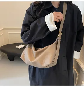 Détail du sac demi-lune beige montrant le cuir grainé et la boucle dorée chic