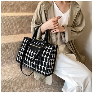 Chic black and white tweed tote bag with leather handles and adjustable shoulder strap