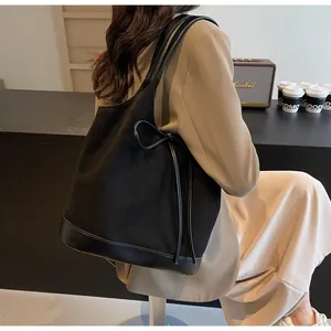 Detailed side view of black matte tote bag with leather bow decoration on model