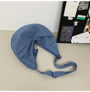Detail of blue nylon dumpling bag featuring dual zippers and woven cord pulls