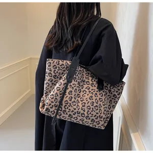 Detailed view of a leopard print tote bag styled with a long black winter coat