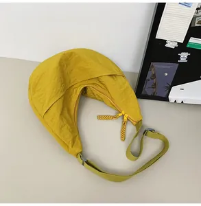 Close-up of yellow nylon crescent bag featuring dual zippers and adjustable strap