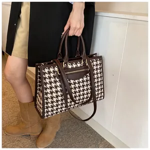 Detail of coffee houndstooth tote bag showing leather handle and metal zipper pocket