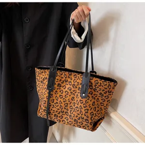 Detail of leopard print tote bag with black leather handles and reinforced metal studs