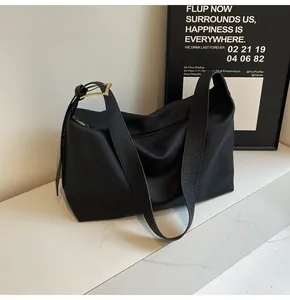 Détail du sac à bandoulière en cuir noir texturé avec sangle large et boucle dorée