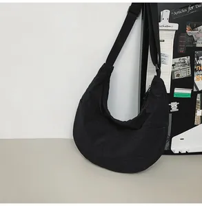 Detail view of the black nylon crescent bag with adjustable strap and smooth zipper closure