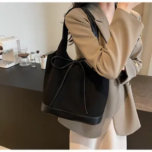Detail of matte black tote bag with bow accent and leather stitching in city scene