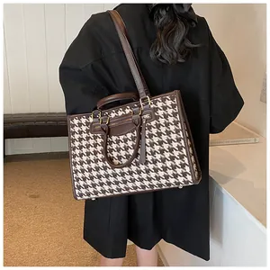 Classic houndstooth tote bag with brown leather trim shown being worn on the shoulder