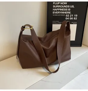 Gros plan sur la texture du cuir grainé marron foncé et la boucle de la bandoulière