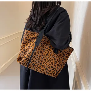 Leopard print tote bag in brown suede shown on shoulder against a minimalist corridor