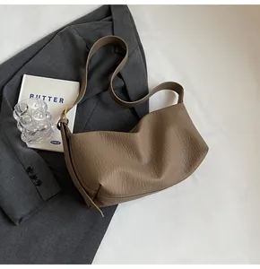 Détail du sac demi-lune kaki foncé avec texture cuir grainé et boucles dorées mates