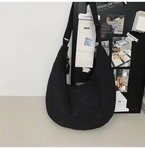 Detail of waterproof nylon crescent bag featuring adjustable wide shoulder strap in black