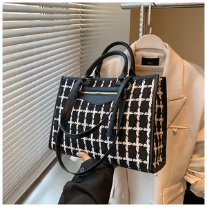 Detail of checkered tote bag showing leather handles and adjustable shoulder strap