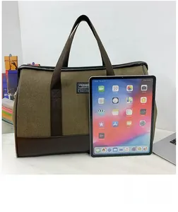 Large olive canvas travel bag shown next to a tablet to demonstrate its spacious capacity