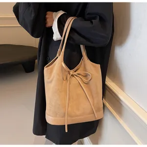 Detail of matte suede tote bag with bow tie decoration and high quality stitching texture