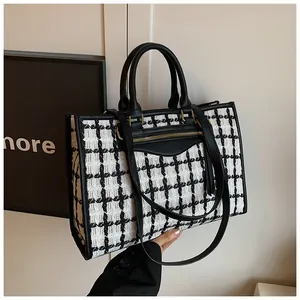 Detail of tweed tote bag showing black and white check pattern with gold zipper pocket