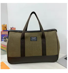 Detail shot of the large olive canvas travel bag on a desk with laptop background