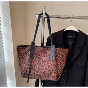 Close-up of leopard print tote bag hanging with a black blazer on a minimalist metal rack