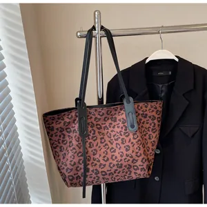Detail of the leopard print pattern and black shoulder straps on a large tote bag