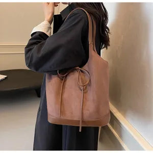 Close-up of caramel brown tote bag with suede texture and bow drawstring detail