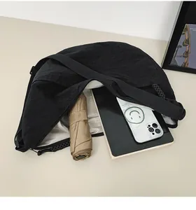 Detail shot of black crescent bag interior holding a tablet, phone, and folding umbrella